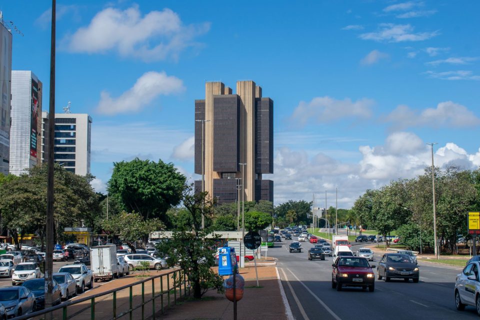 Vista externa do edifício do Banco Central do Brasil em Brasília, sob um céu colorido.