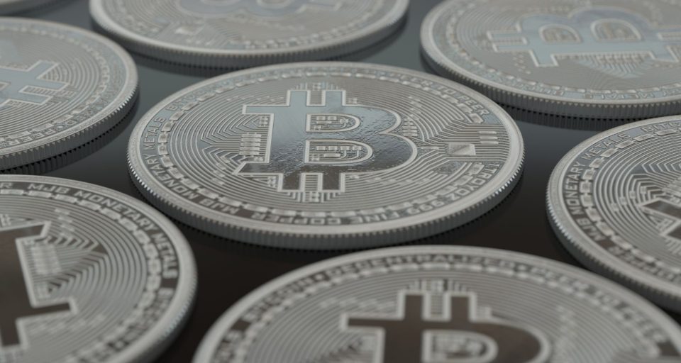 Moedas prateadas de Bitcoin em close-up, representando ativos digitais e criptomoedas