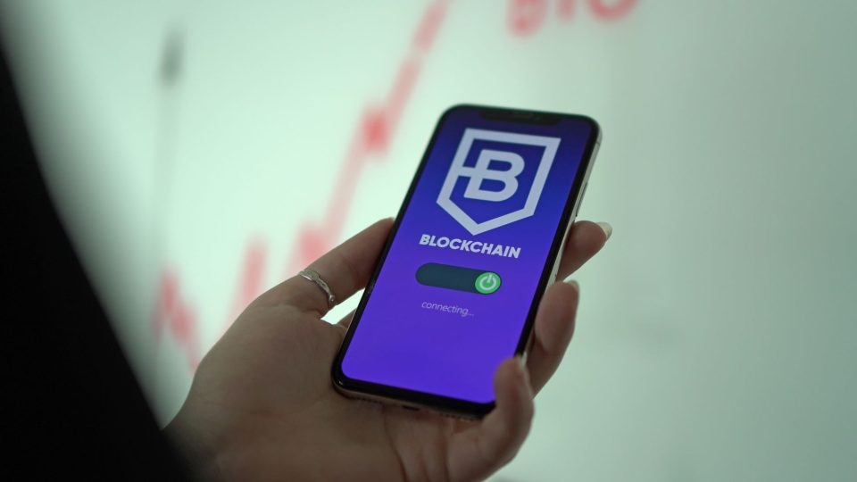 Mão segurando um smartphone que exibe uma carteira digital de criptomoedas.